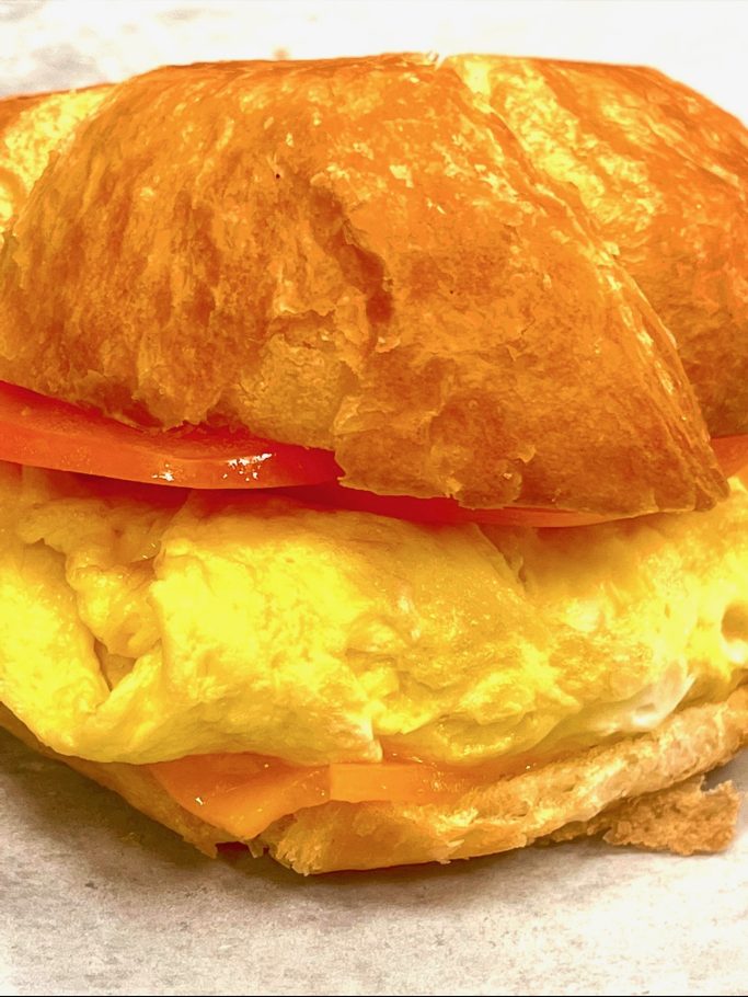 Delicious croissant sandwich with egg, cheese, and tomato slices.